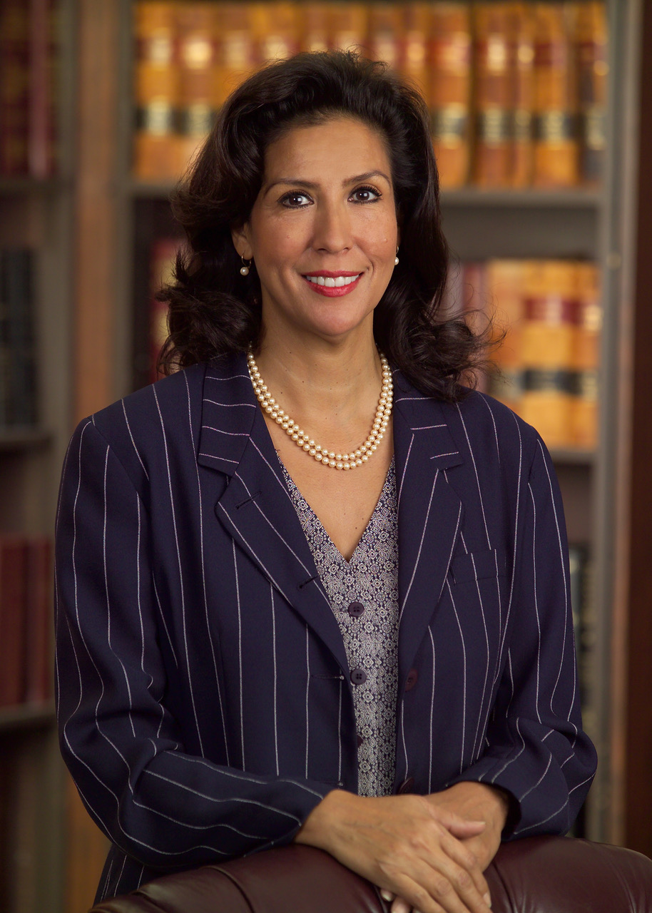 Judge Vanessa Velasquez in a pinstripe suit in a law library