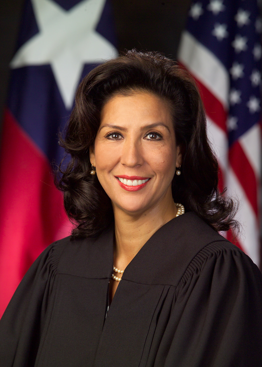 Judge Vanessa Velasquez in judicial robes before the Texas and American flags